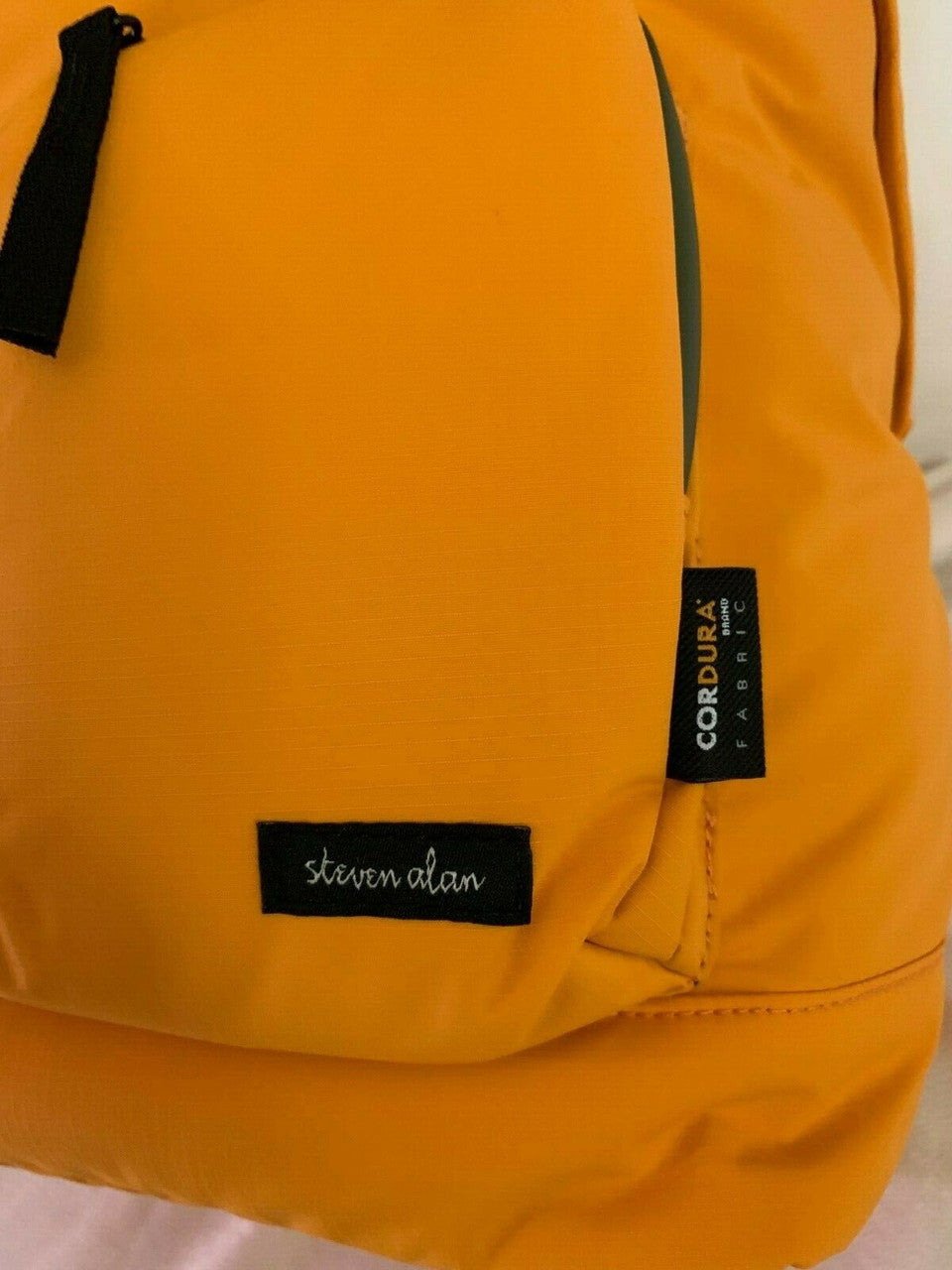 Close-up of an orange backpack with brand labels.