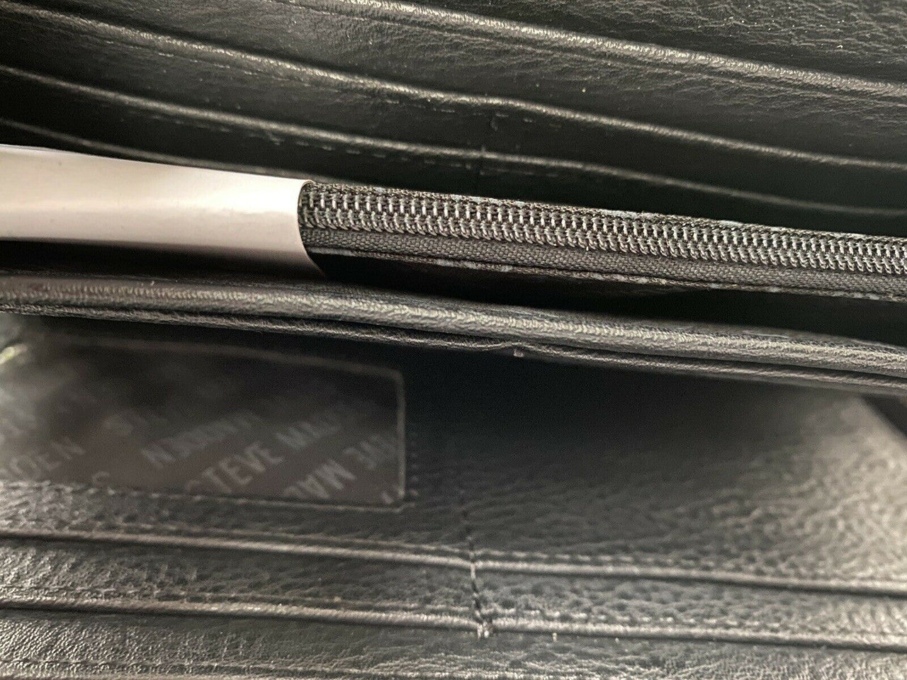 Close-up of a zipper on a black leather bag.