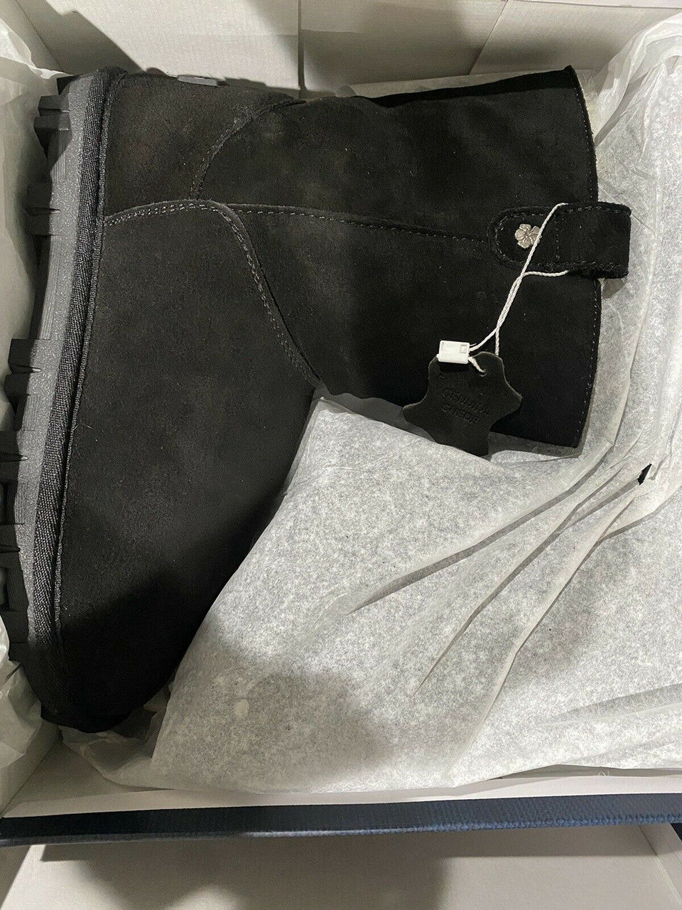 Black boots and gray pants in a box