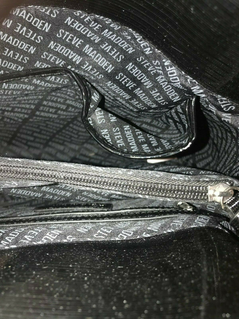 Close-up of a black shoe with a logo pattern and zipper.