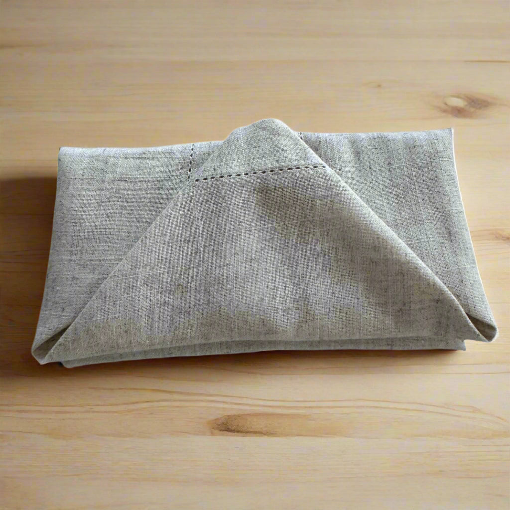 Natural beige linen dinner napkin with delicate embroidered detail and hemstitched edges, 17 x 17 inch reusable cloth napkin styled on an elegant table setting