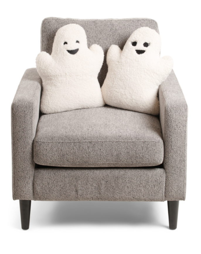 Two plush ghost toys sitting on a gray armchair against a white background