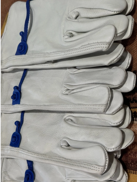 Stack of white leather gloves with blue laces on a textured surface