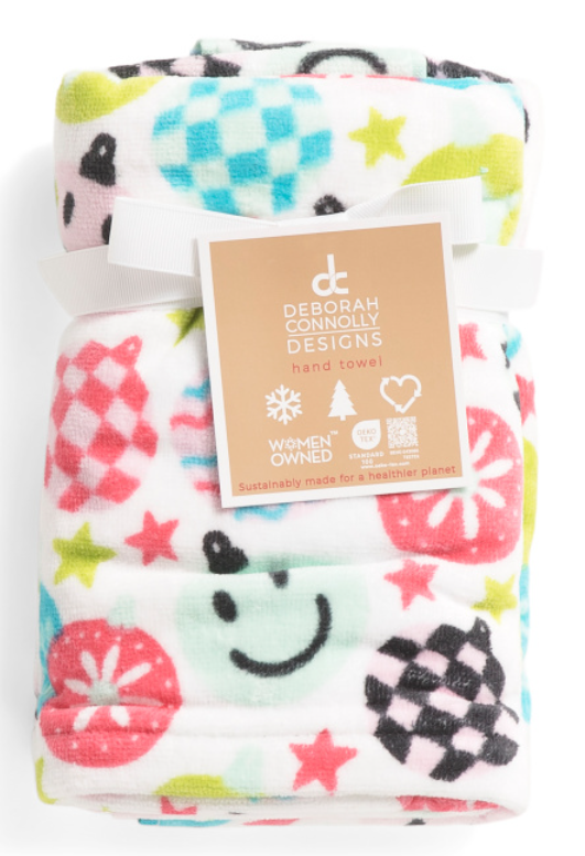 Set of 2 hand towels with a colorful holiday-themed printed design in red, green, blue, and pink with stars, smiley faces, and plaid patterns. 16 inches wide by 28 inches long