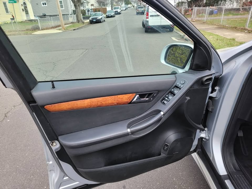 Driver-side interior door panel of 2009 Mercedes-Benz R350 showing window controls, wood trim, and door handle design