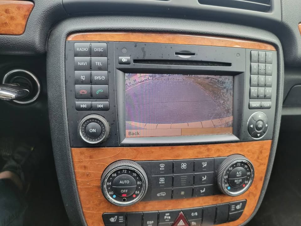 Center console of 2009 Mercedes-Benz R350 showing infotainment screen with active backup camera, wood trim, and climate control buttons