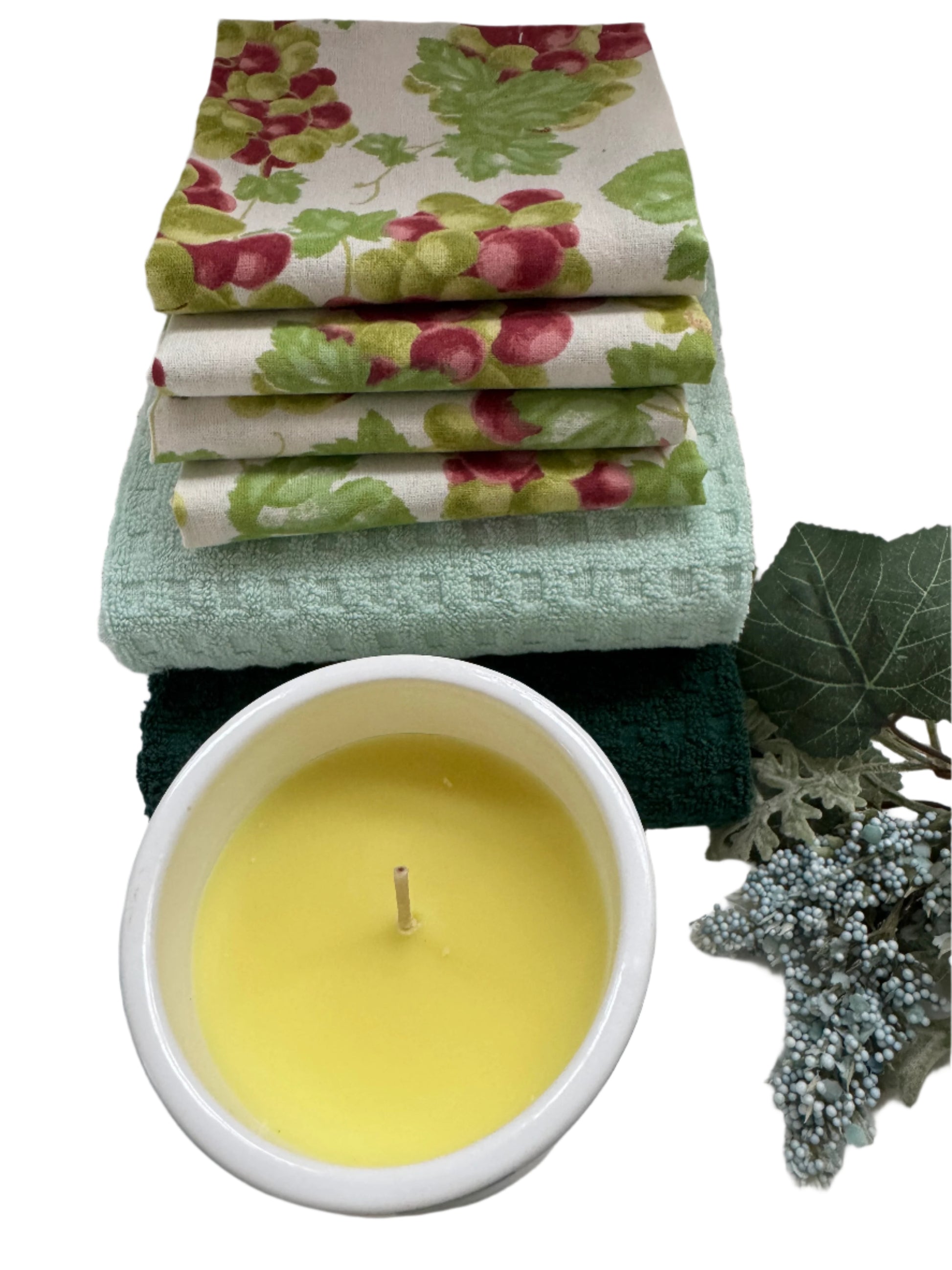 Charming kitchen gift set featuring 4 hand-screen printed cotton napkins with a grape design, 2 cotton towels in soft pastel green and teal, and a yellow scented candle. Perfect for enhancing your kitchen or as a thoughtful gift. The set showcases elegant, functional kitchen essentials