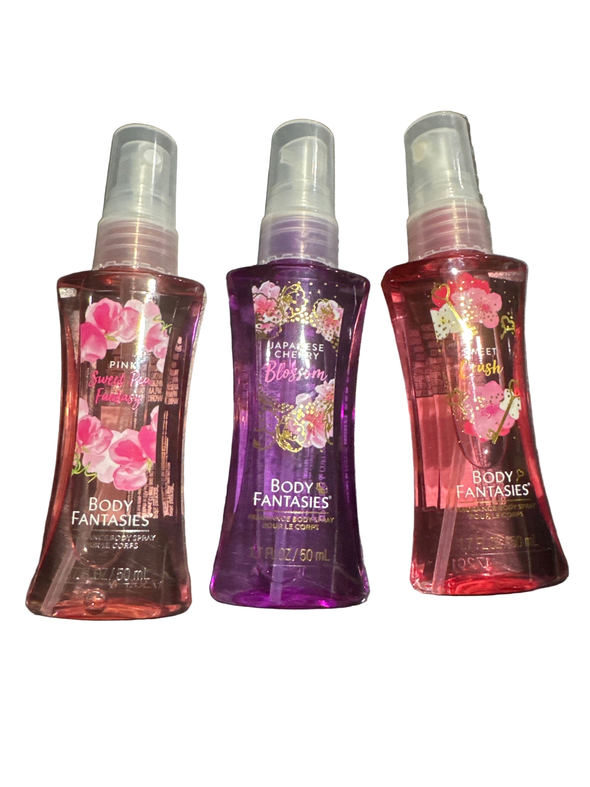 Three bottles of Body Fantasies spray on a dark surface