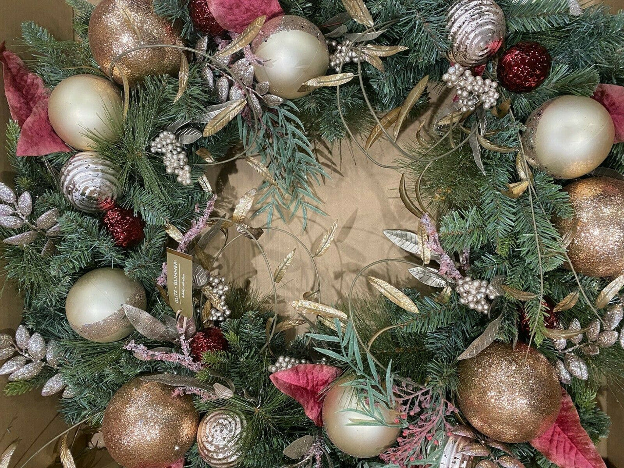A 32 inch faux pine wreath with rose gold ornaments and glitter decorations, designed by Martha Stewart.