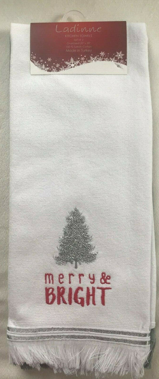 A white kitchen towel with a Christmas tree and the text 'merry & bright' printed in red, displayed on a counter.