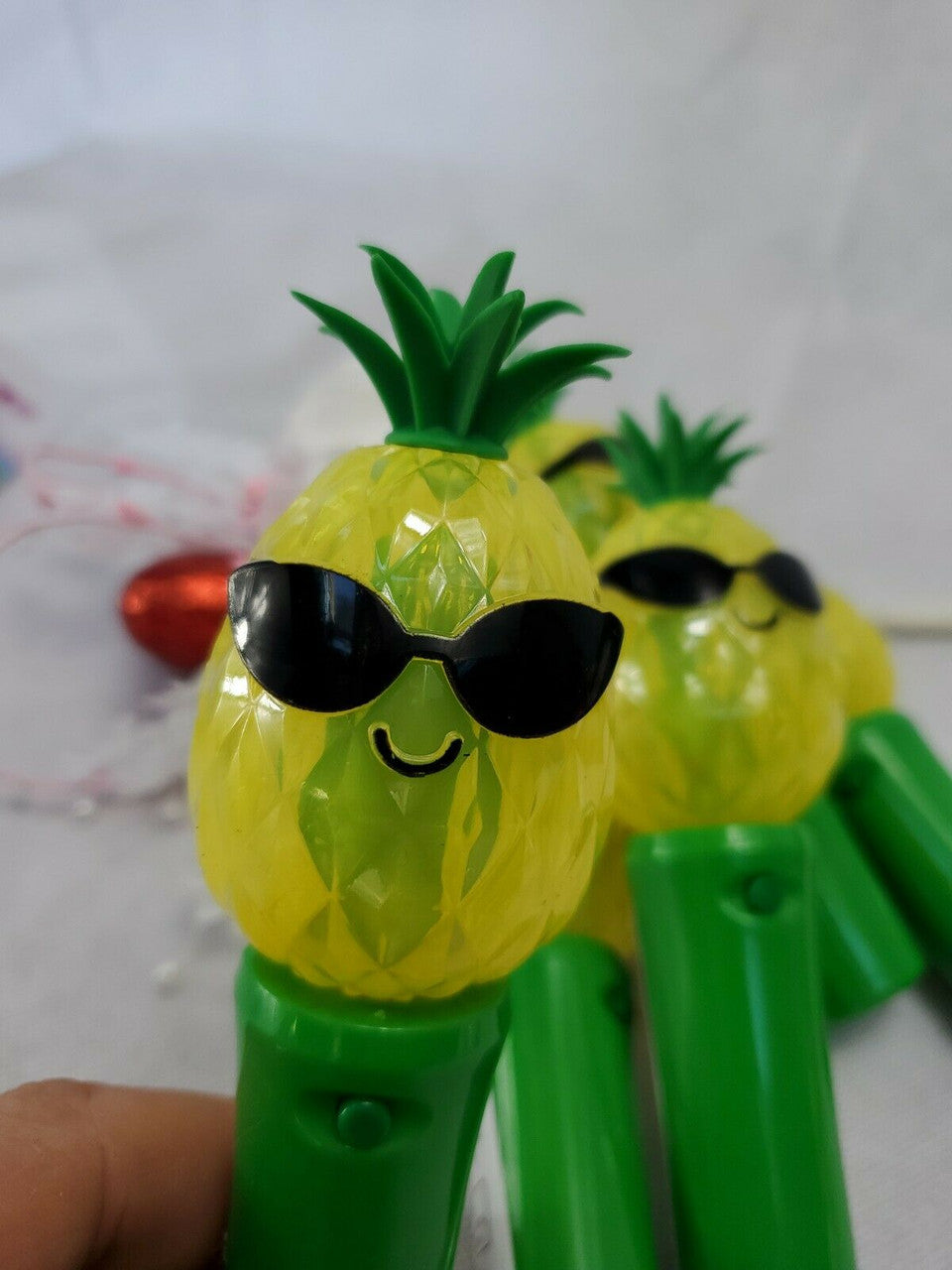 Set of five handheld pineapple-shaped light-up spinner toys, battery operated.