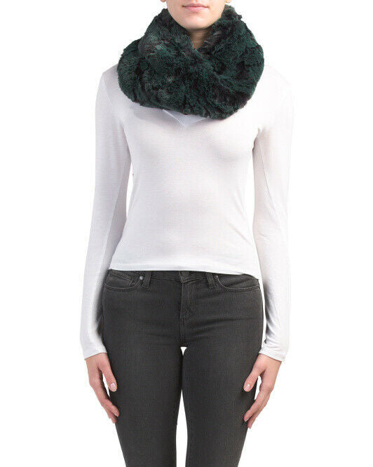 A woman wearing a white top and black pants, with an emerald-green and black faux fur twisted snood