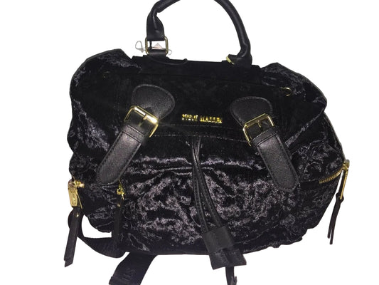 A black medium-sized backpack with gold zippers and closures, displayed on a white surface with a floral pattern.