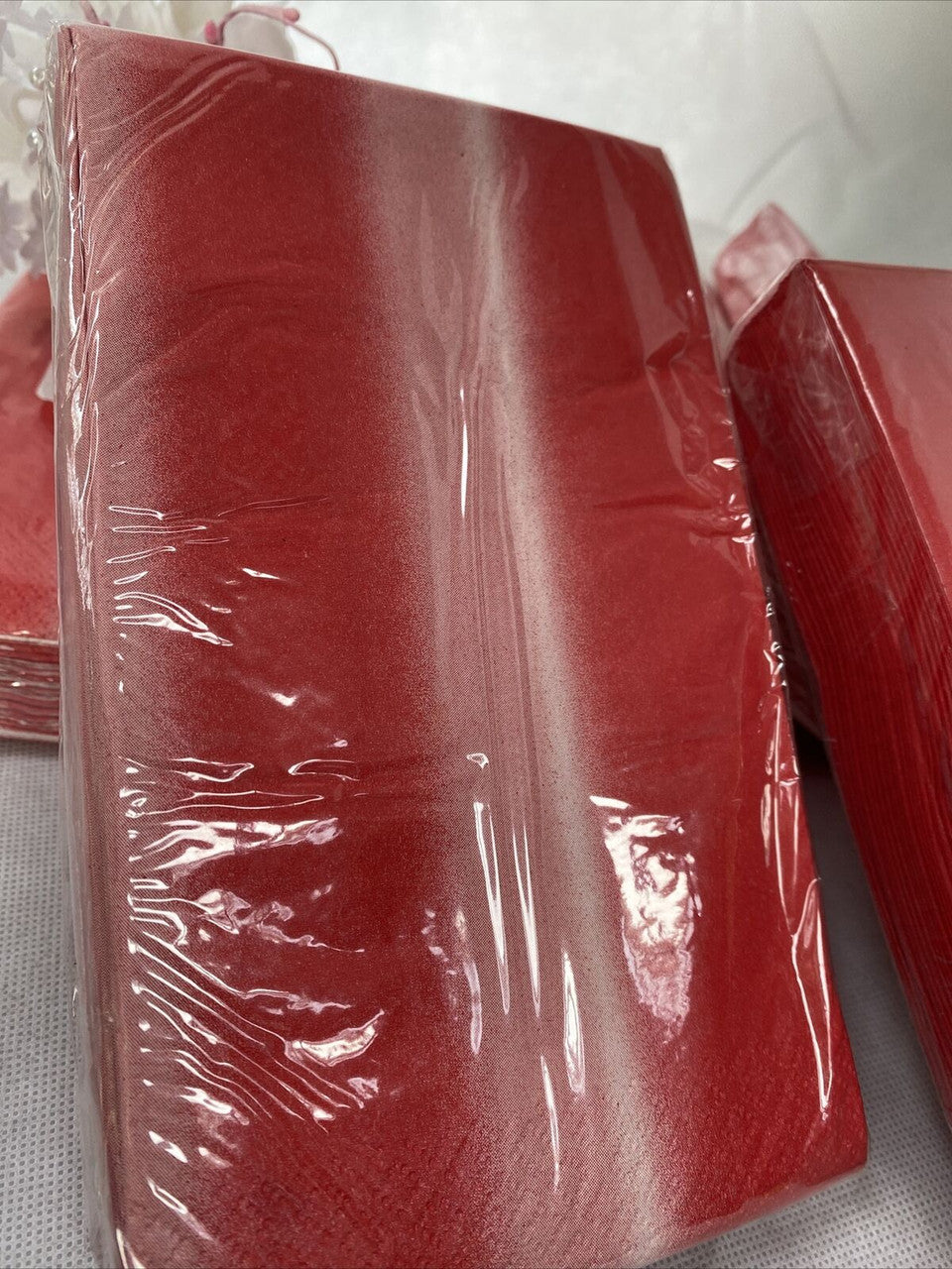 Six packs of red ombre paper guest napkins wrapped in packaging, 3-ply disposable napkins by Diva made in the USA
