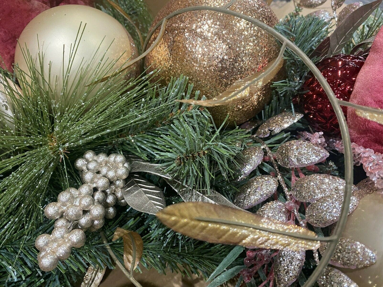 Close-up of Christmas decorations with gold and silver ornaments on greenery.