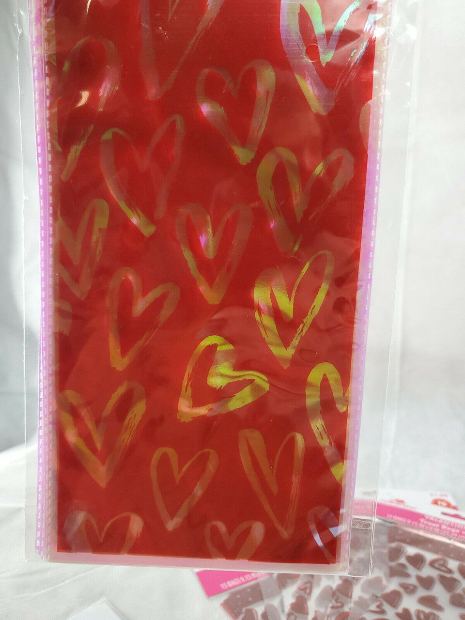 Six packs of Valentine’s Day treat bags in red with multi-colored hearts, mixed counts of ten and fifteen bags per pack.