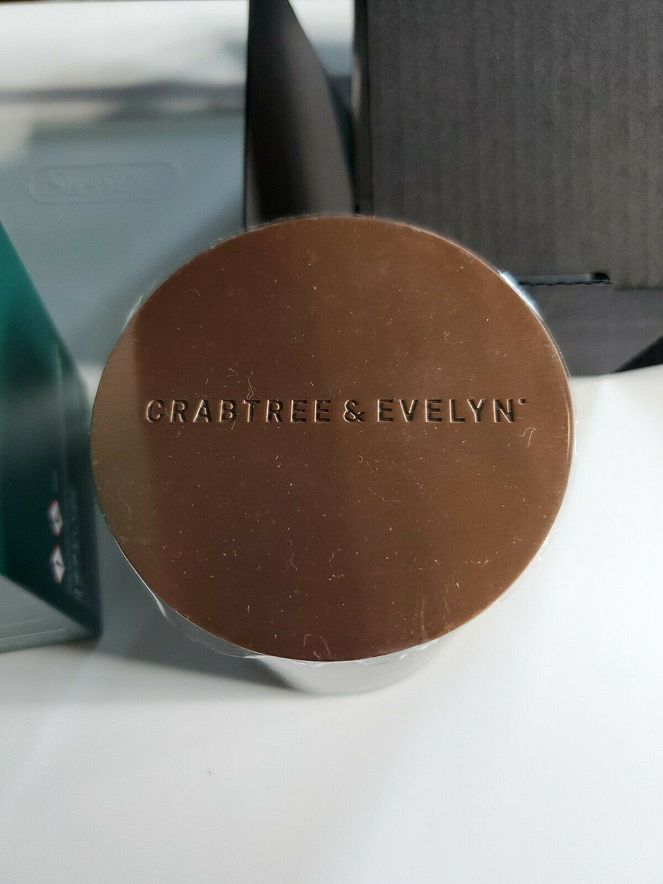 Crabtree & Evelyn Raw Instinct scented candle in green glass jar with copper lid, 8.8 oz premium soy wax blend.