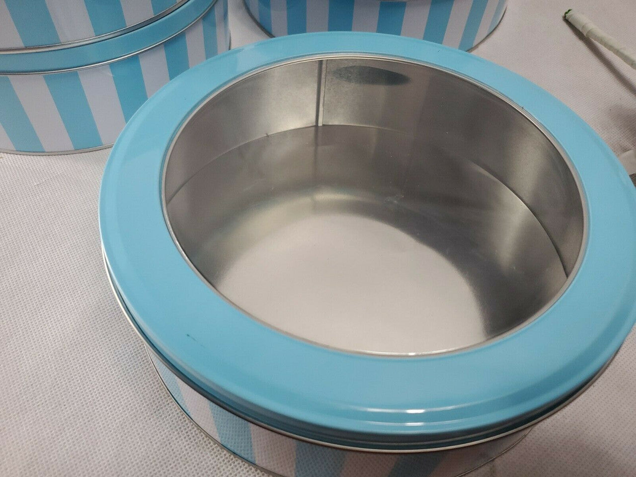 Metallic container with blue rim on a light gray surface