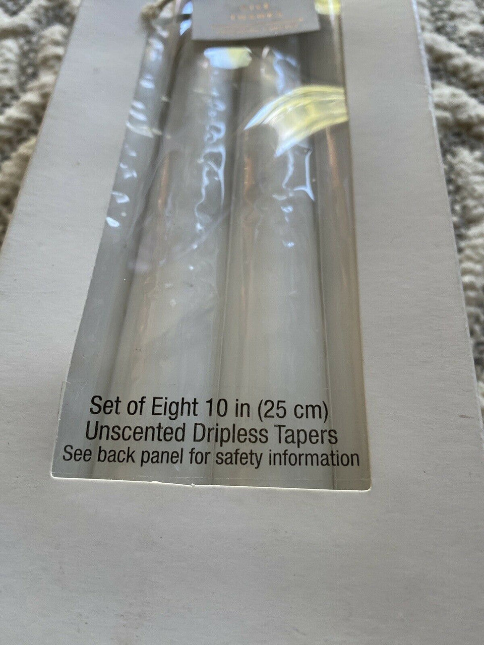 Set of 8 dripless unscented white taper candles in original packaging, ideal for elegant home decor or events