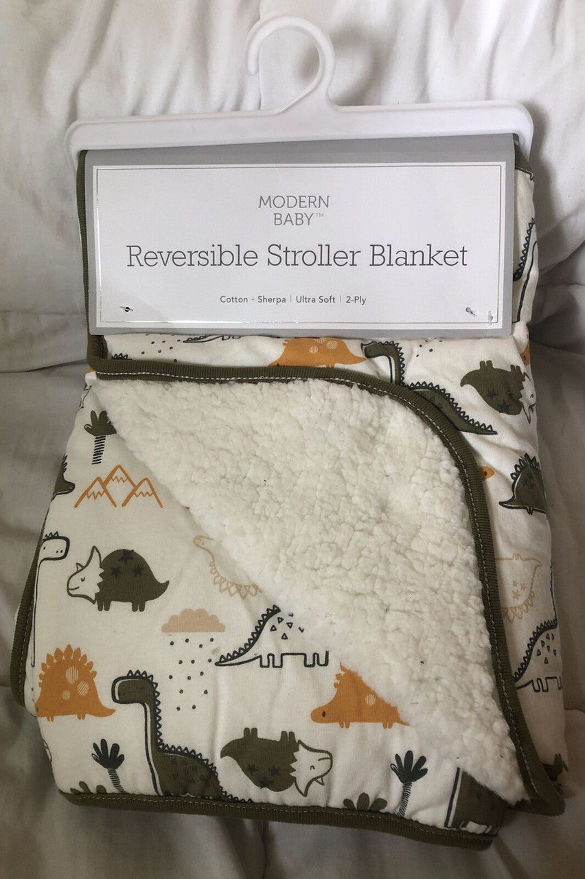Reversible stroller blanket with dinosaur pattern on a hanger.