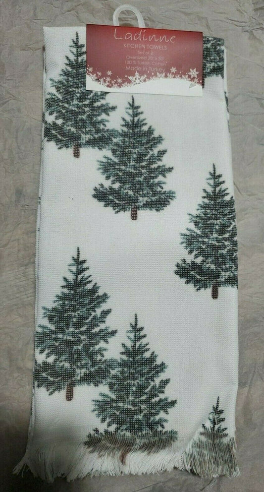 A pair of kitchen towels with a white background and a green tree pattern, displayed with its packaging behind.