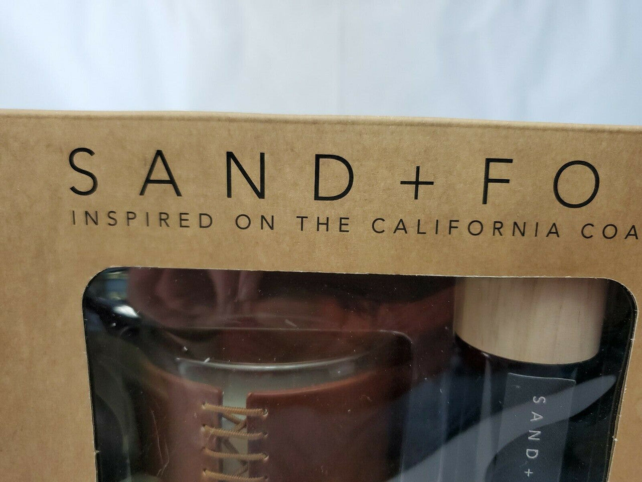 Gift set with Sand + Fog 8 oz teakwood candle and 100 ml room spray in amber containers, boxed for gifting.