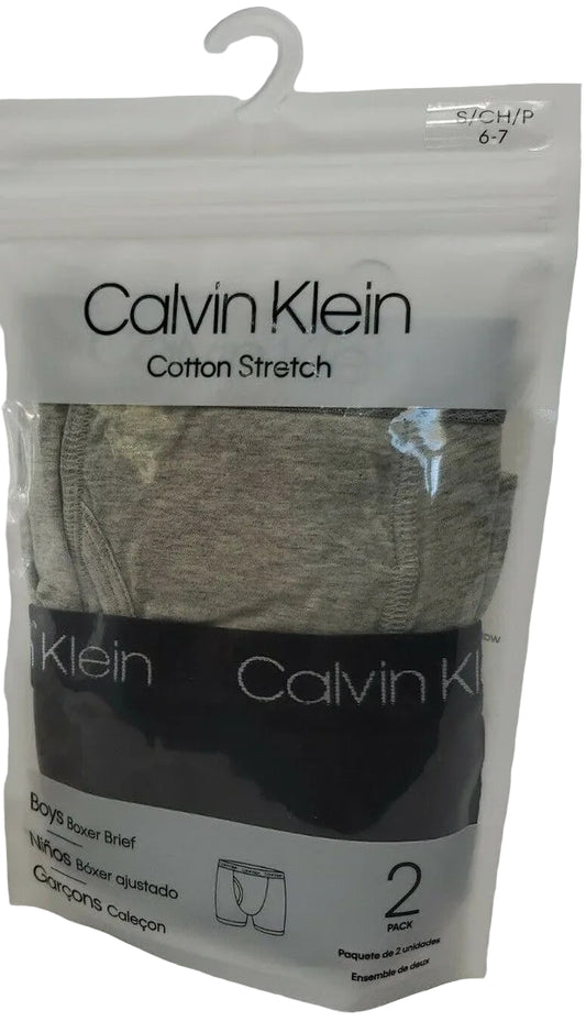 A pack of Calvin Klein boy's boxer briefs in a transparent plastic packaging, displaying two pairs of boxer briefs in gray and black colors.