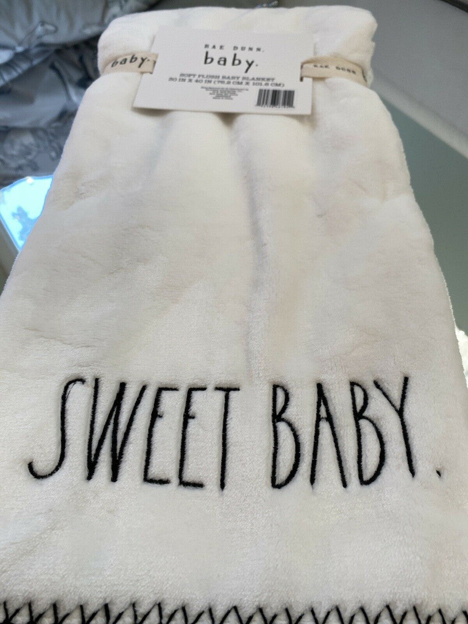 White baby blanket with 'sweet baby' text on a soft background