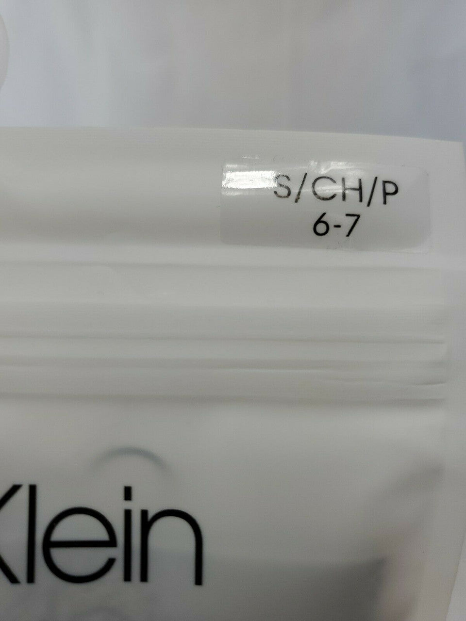 Close-up of a label on a white garment with 'Klein' branding.