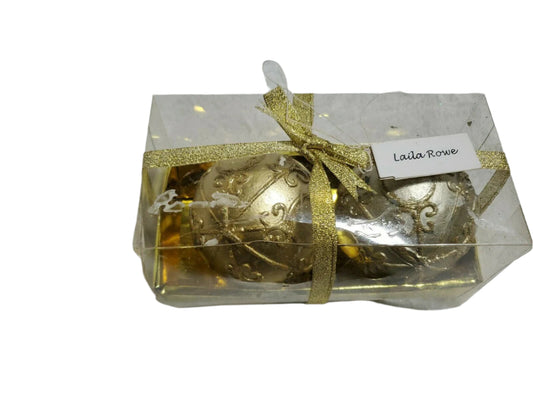 Set of two round ball candles in gold and silver by Laila Rowe, packaged in a clear gift box with gold ribbon.