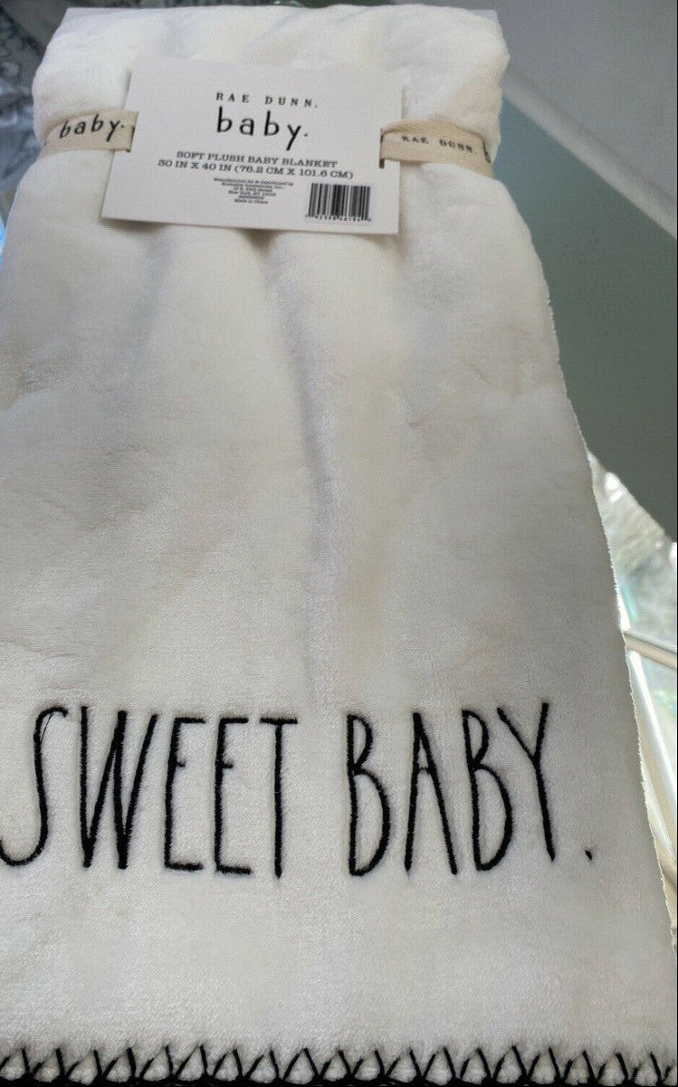 White baby blanket with 'Sweet Baby' text, tag still attached.
