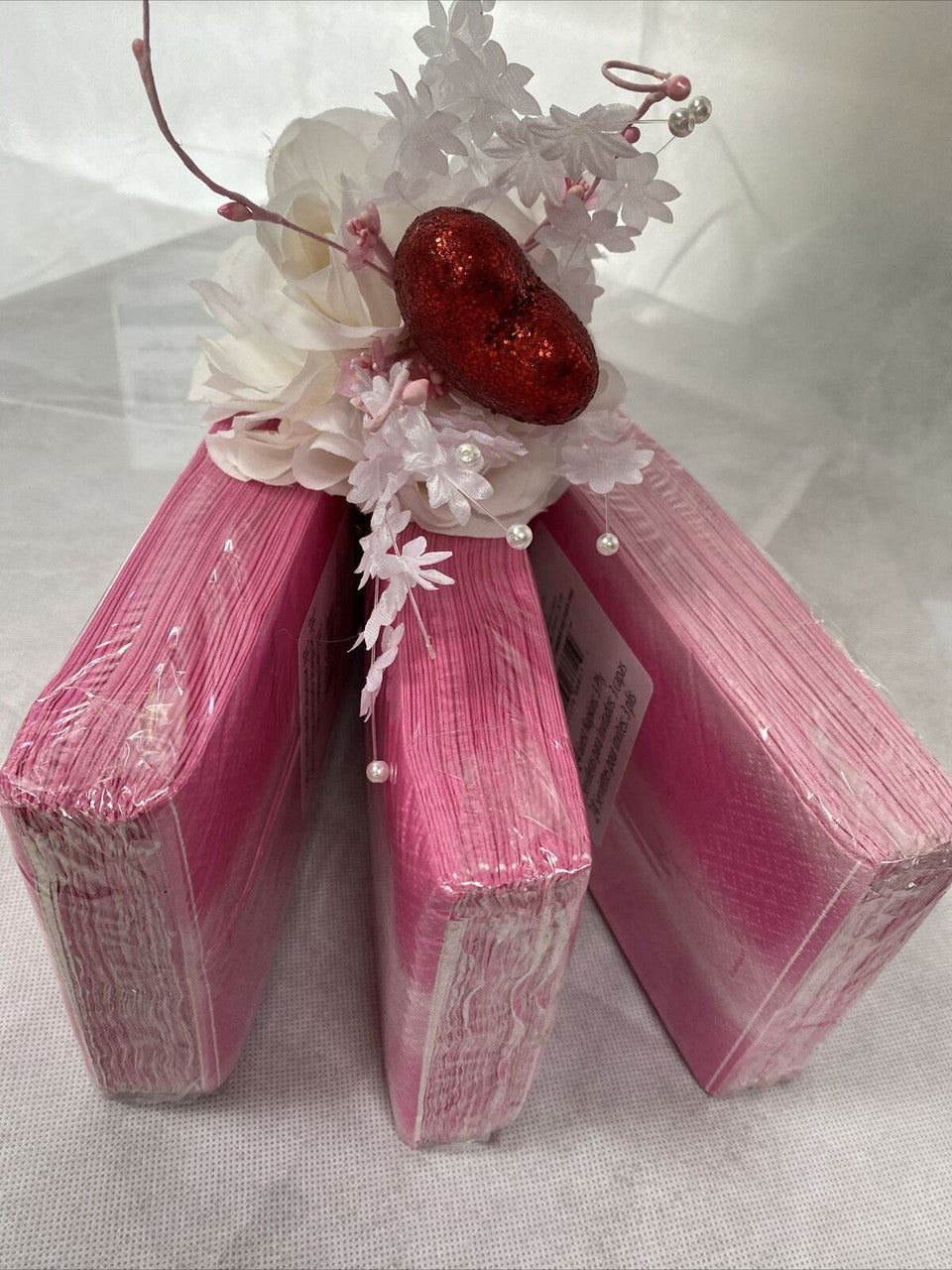 Three packs of pink ombre paper guest napkins wrapped in packaging, 3-ply disposable napkins by Diva made in the USA