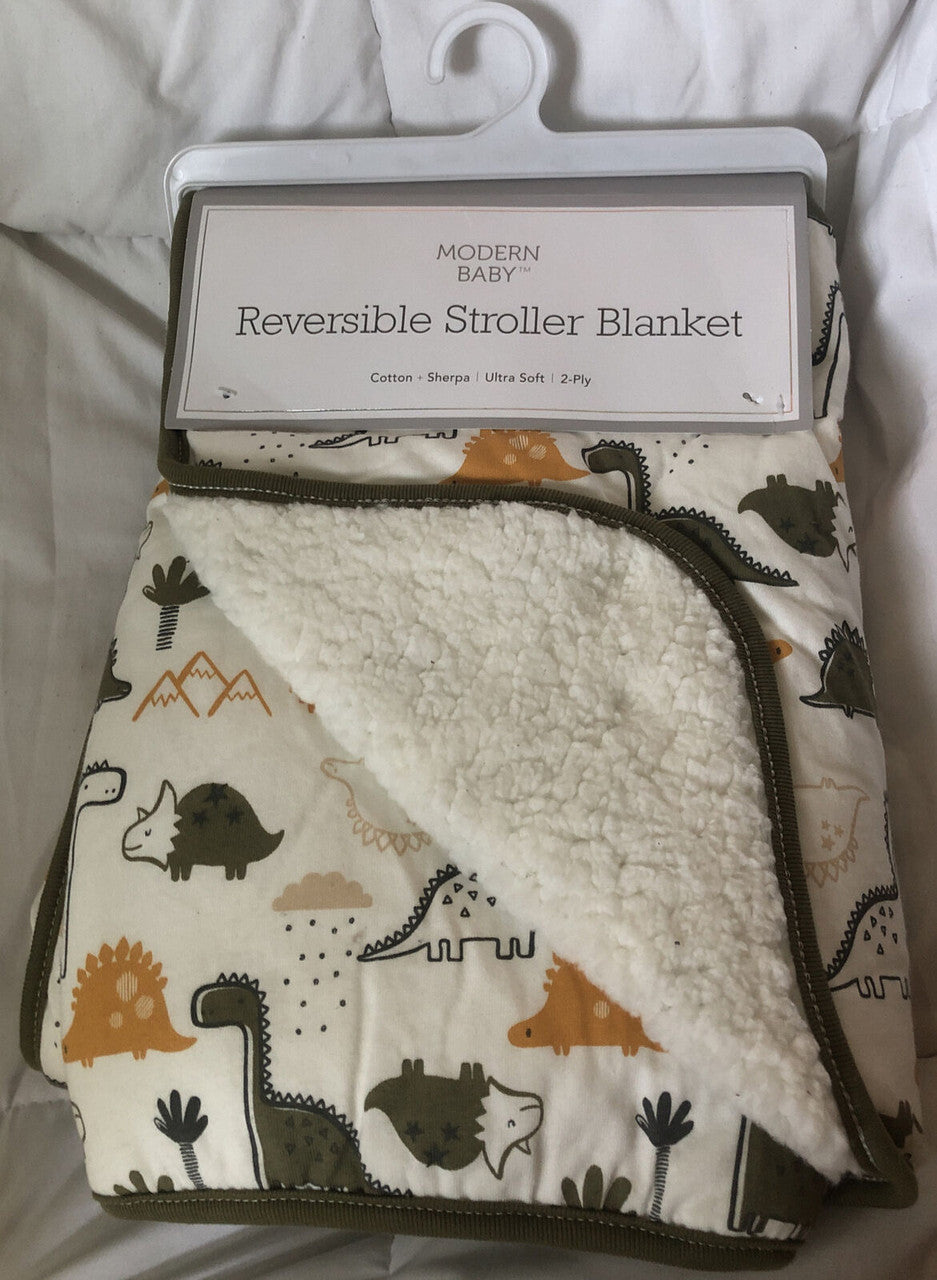 Packaged reversible stroller blanket with a dinosaur design on one side and a sherpa material on the other, labeled as 'Modern Baby' brand.