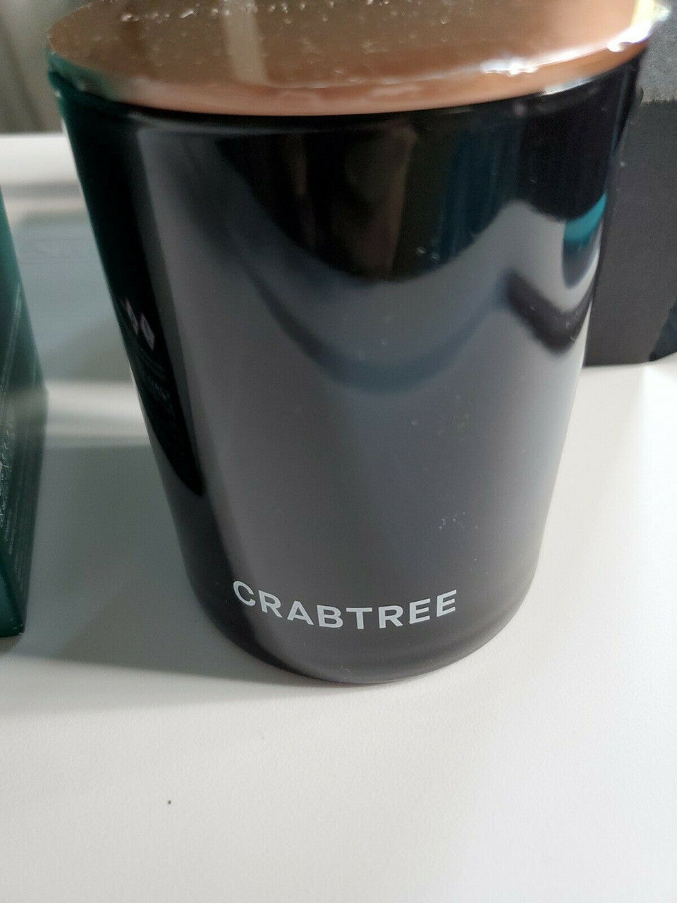 Crabtree & Evelyn Raw Instinct scented candle in green glass jar with copper lid, 8.8 oz premium soy wax blend.