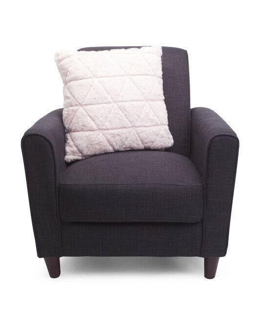 A faux fur throw pillow with a quilted design and zippered cover, in a color described as blush, placed on a dark chair.