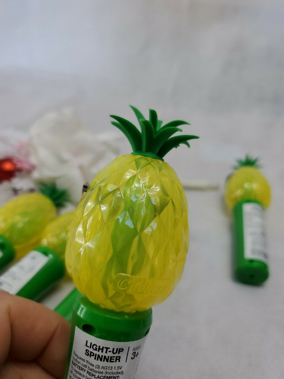 Set of five handheld pineapple-shaped light-up spinner toys, battery operated.