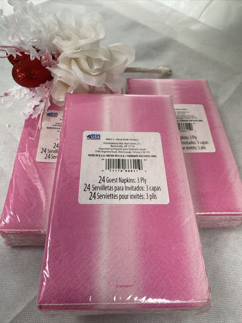 Three packs of pink ombre paper guest napkins wrapped in packaging, 3-ply disposable napkins by Diva made in the USA