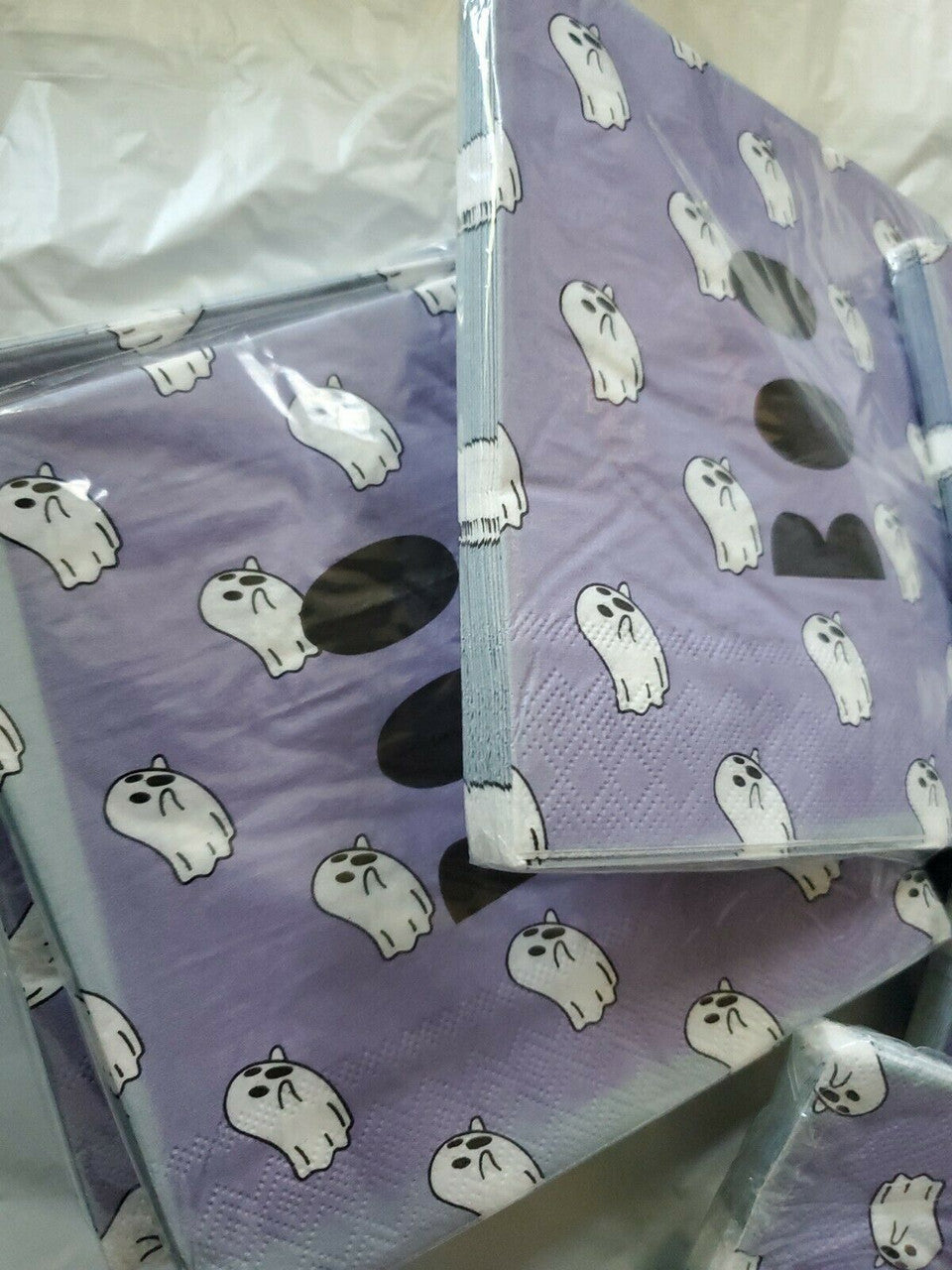 Stack of purple Halloween paper napkins with white ghost and BOO design in packaging