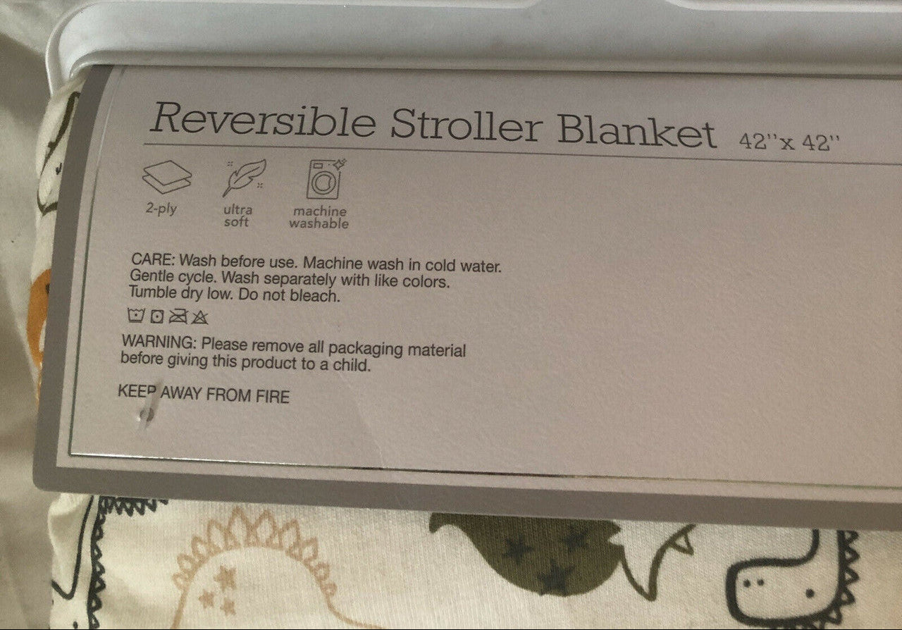 Reversible stroller blanket with dinosaur pattern on a hanger.