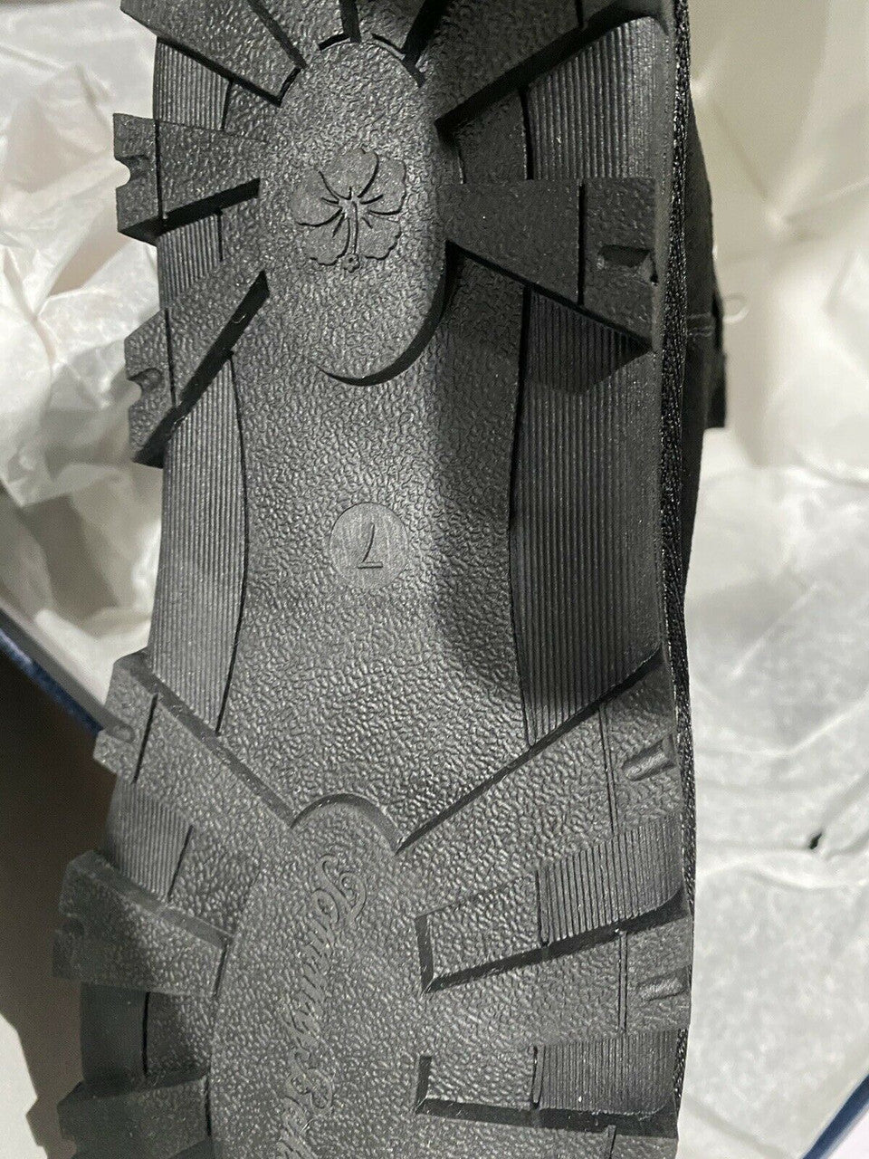 Close-up of a black sole with tread patterns on a white background.