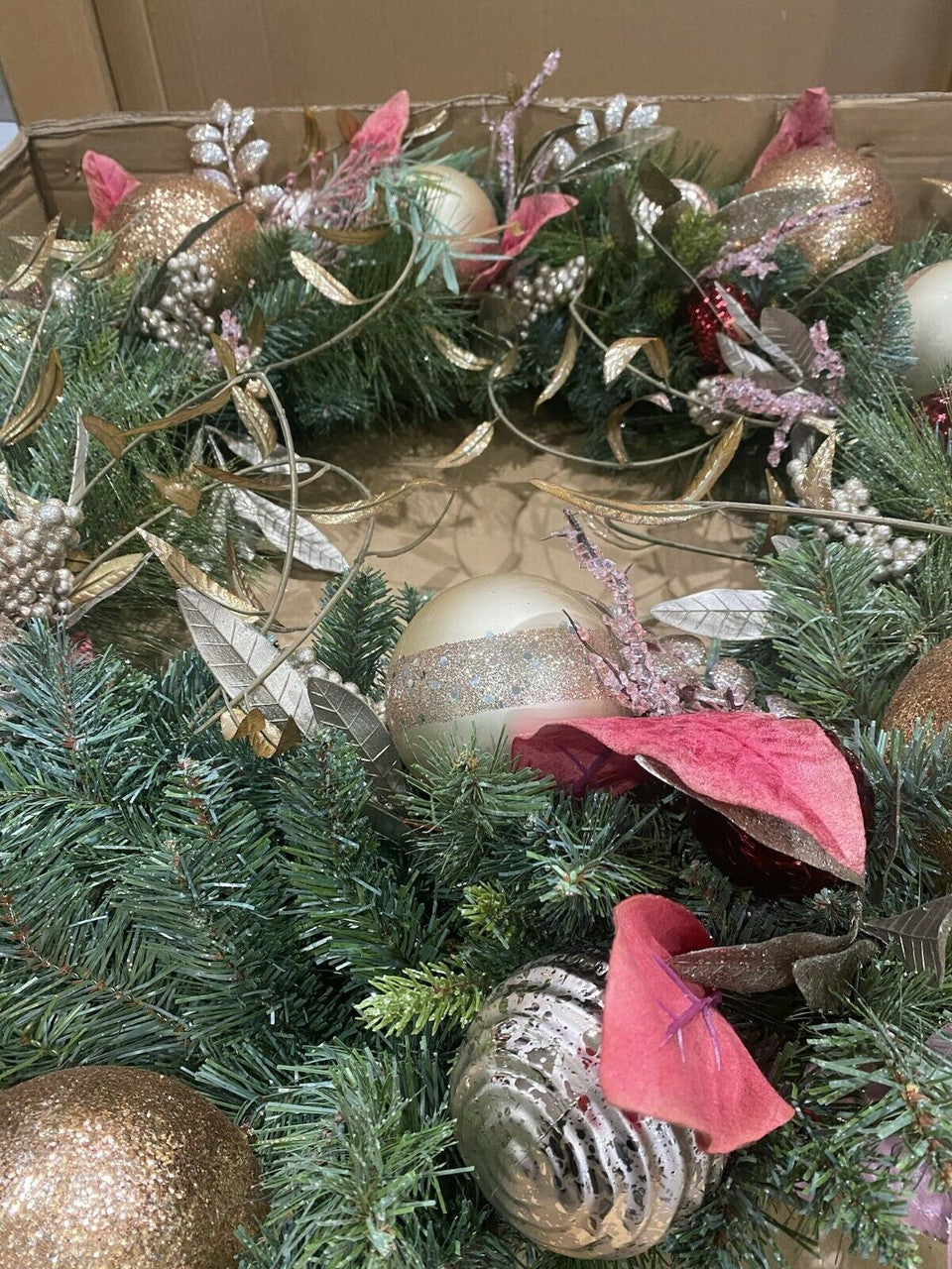Decorative Christmas wreath with ornaments and red leaves.