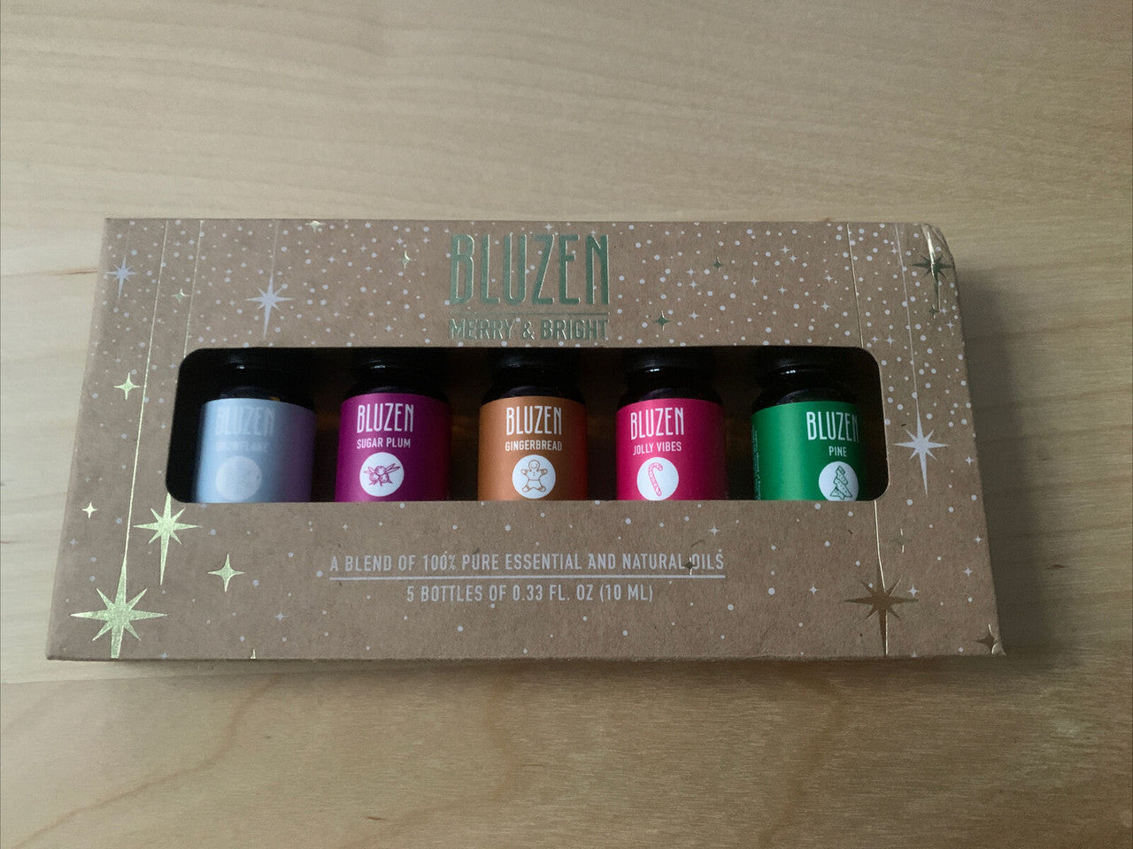 A pack of five Bluzen essential oils in a cardboard box with snowflake, sugarplum, gingerbread, jolly vibes, and pine labels.