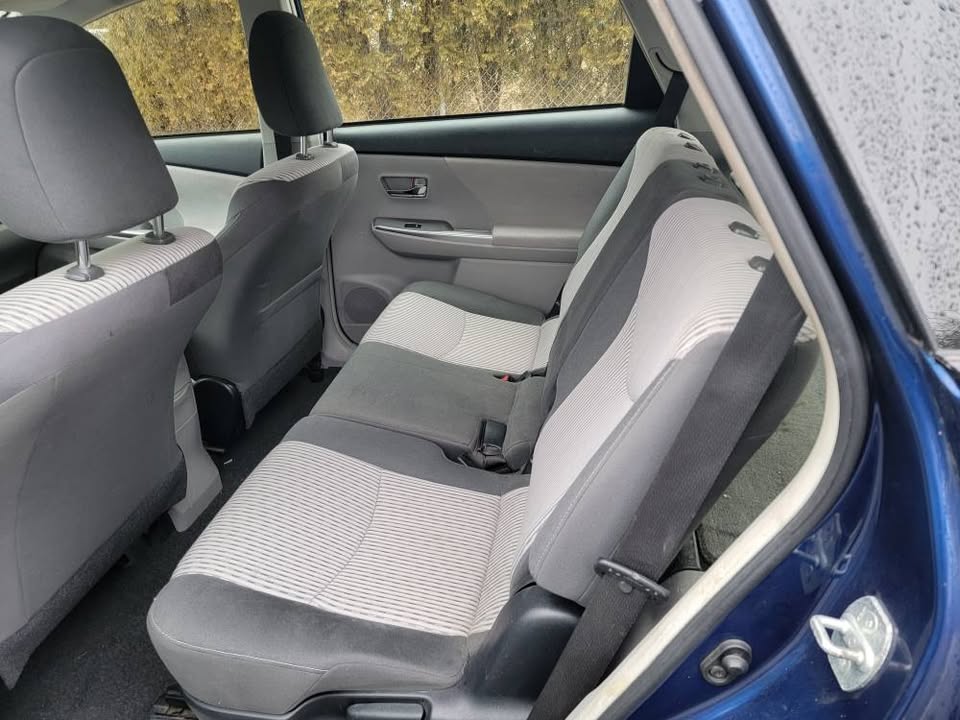 Rear seats of a 2015 Toyota Prius v with two-tone gray cloth upholstery, viewed from the open rear passenger door
