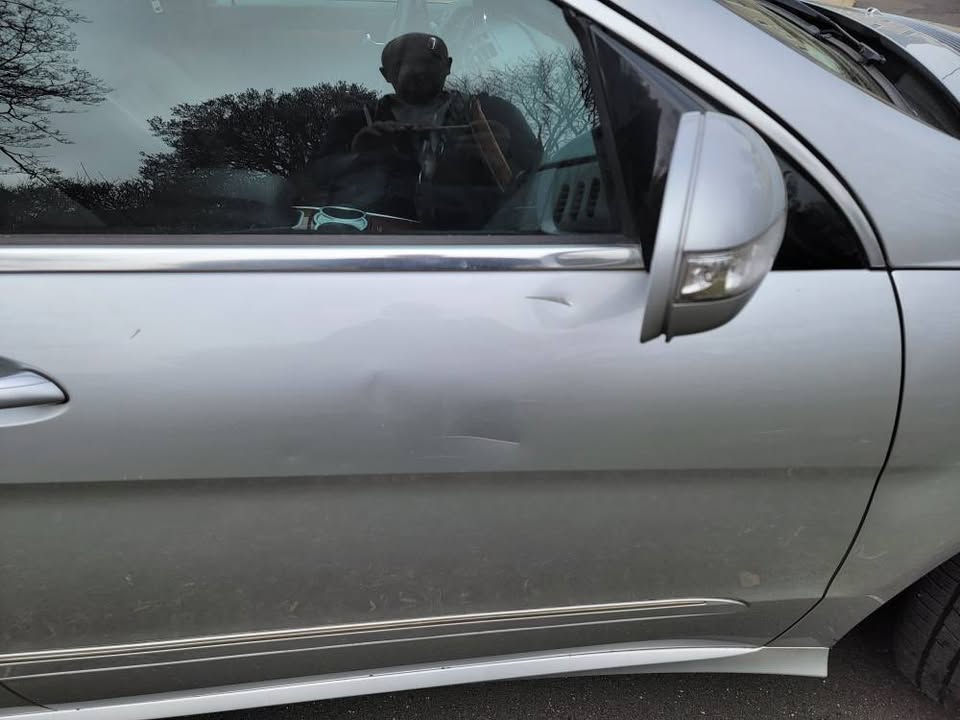 Close-up of driver-side door on 2009 Mercedes-Benz R350 showing small dent and minor scratches near trim and handle