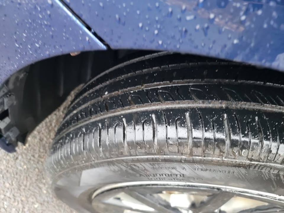 Close-up of a front tire on a blue 2015 Toyota Prius v showing tread depth and wheel well








