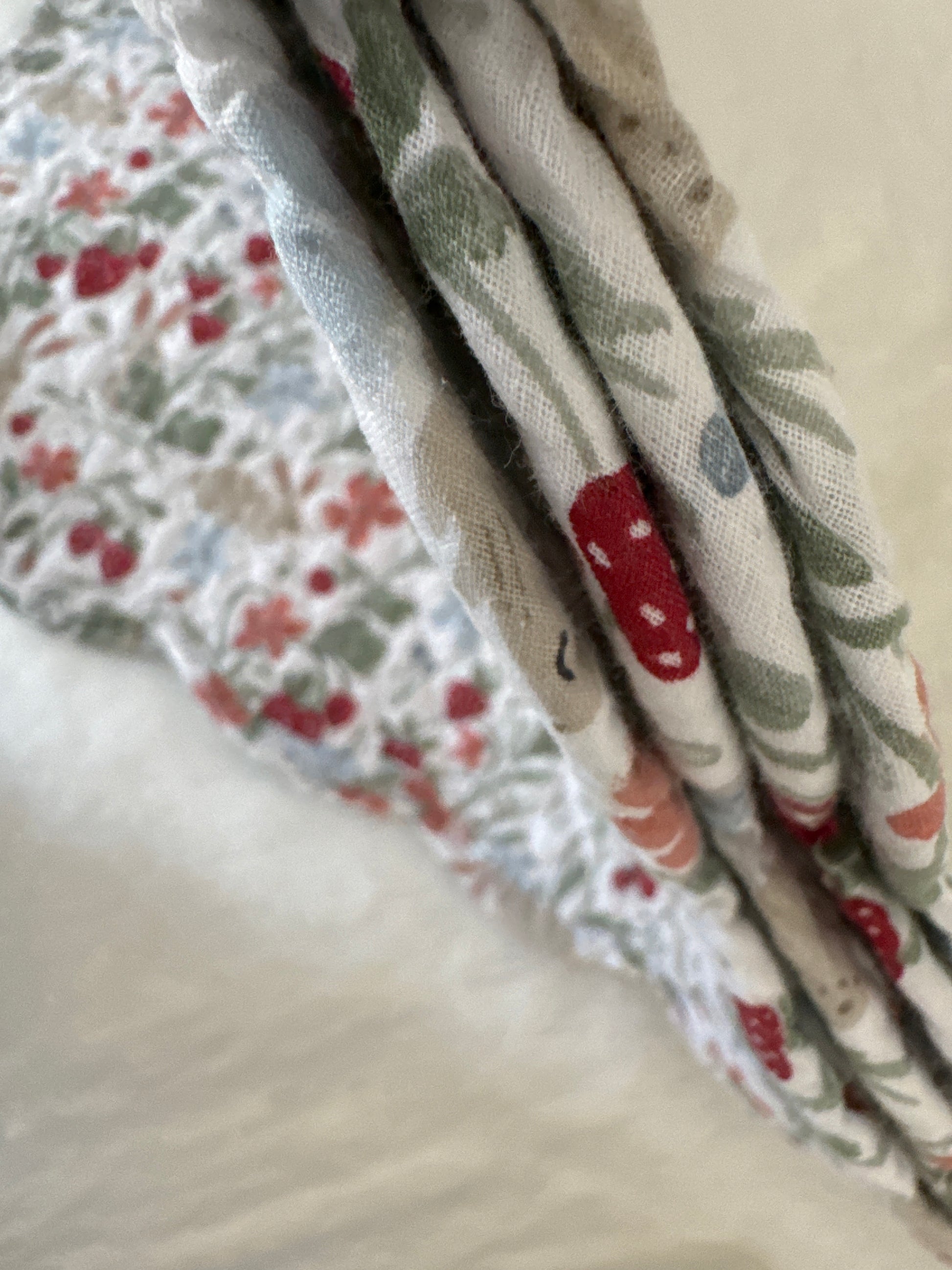 Side view of a stack of placemats with a floral and strawberry design, showcasing the quilted texture of the fabric