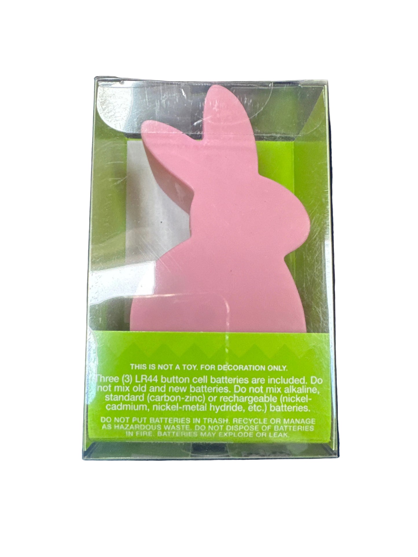 Pink bunny-shaped object in clear packaging with green label on a dark background