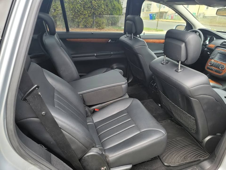 Rear seating view of 2009 Mercedes-Benz R350 showing black leather seats, wood trim, center armrest, and climate vents