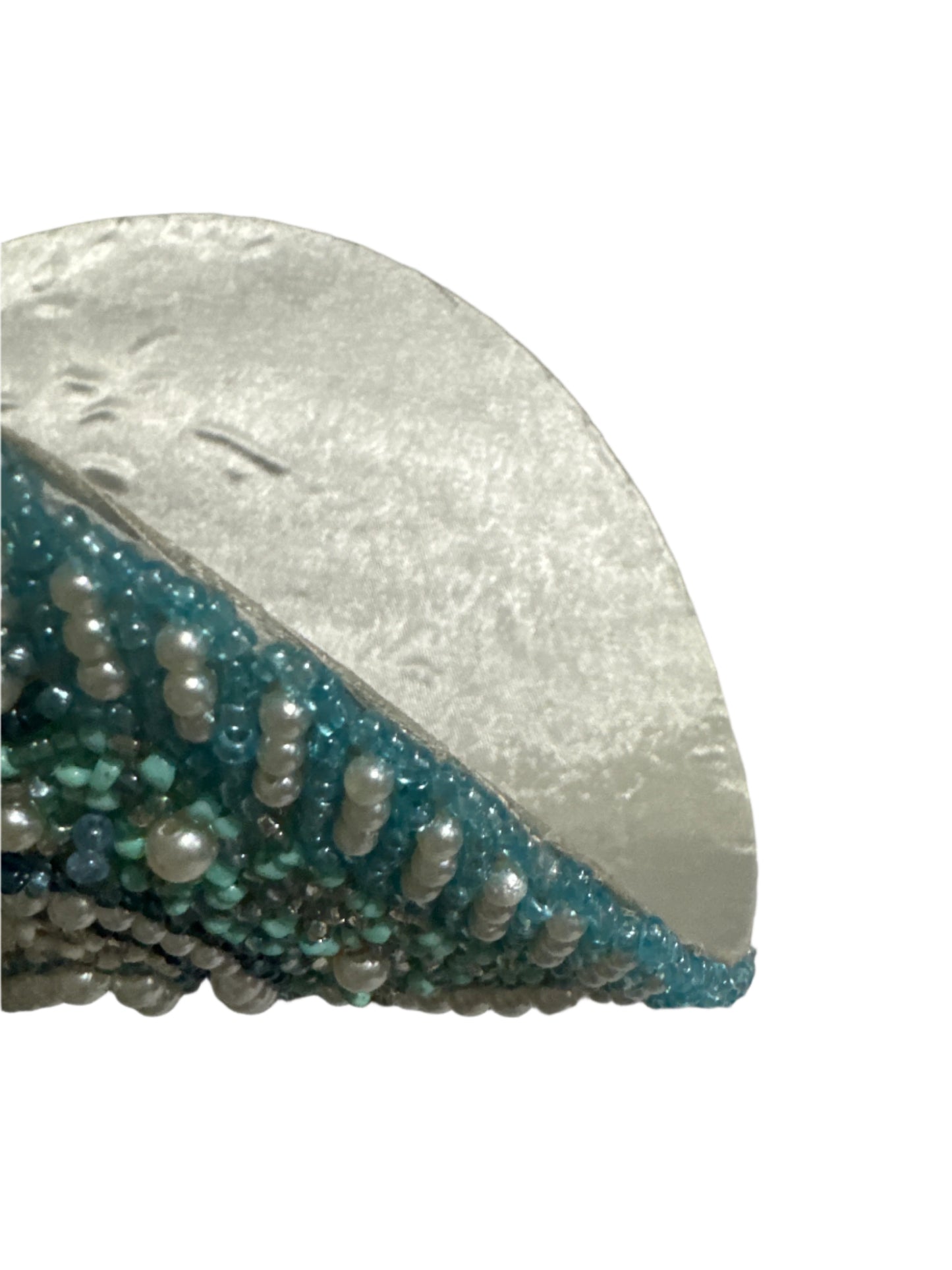 Close-up of a beaded placemat with intricate turquoise and pearl bead detailing along the edge, showcasing the smooth metallic backing and high-quality craftsmanship