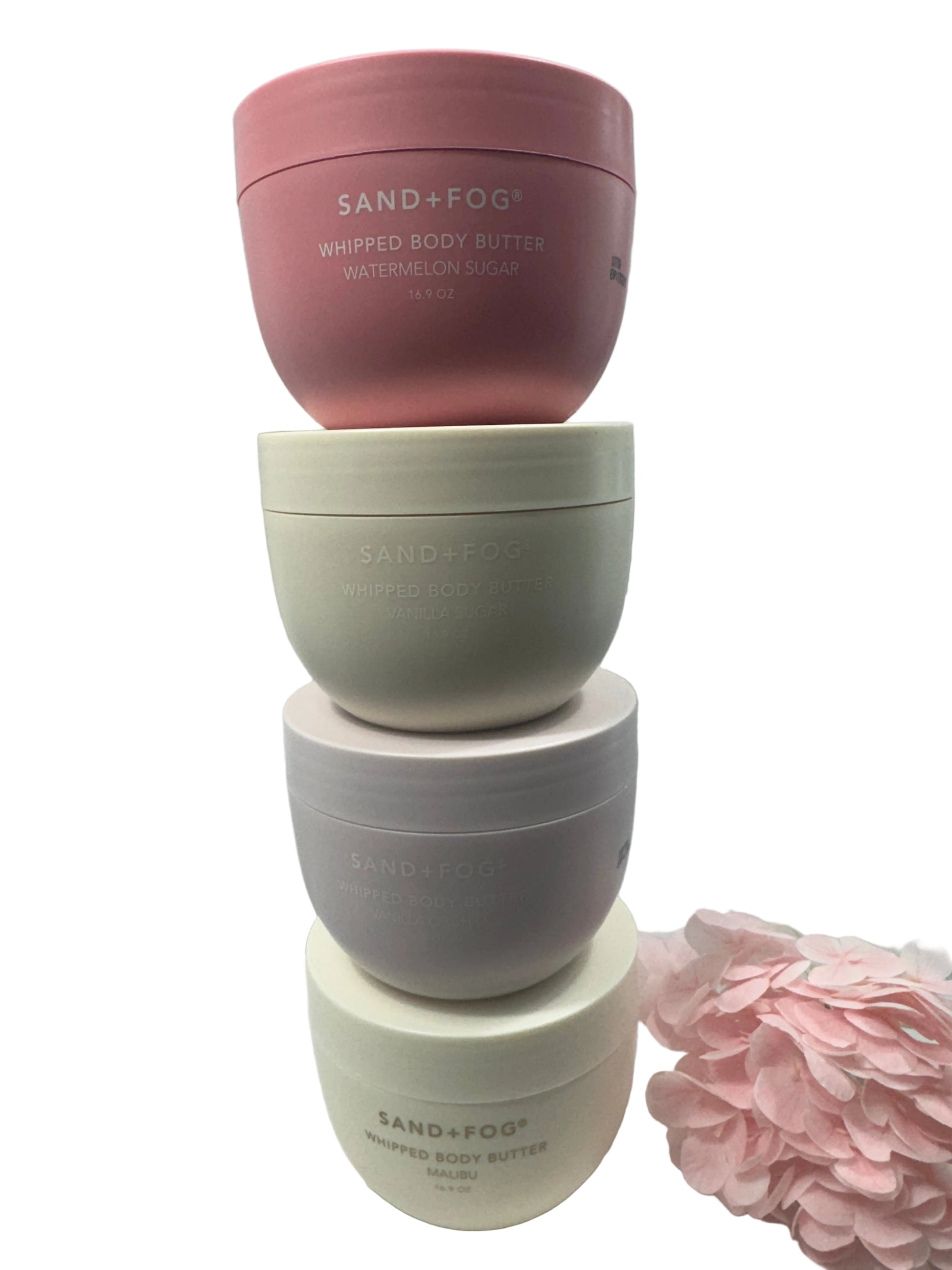 Four cosmetic containers with 'Sand & Fog' branding on a light background